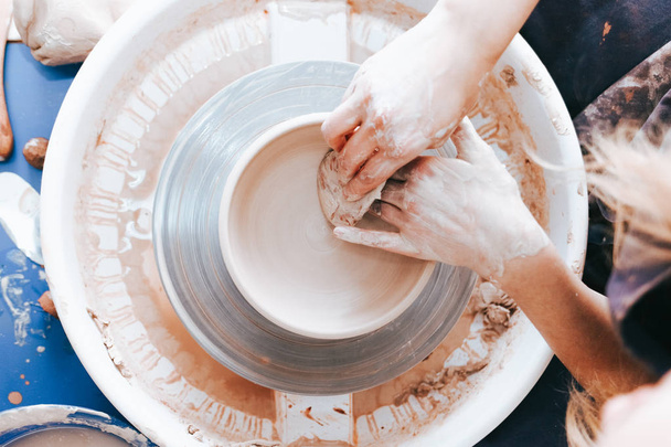 Процесс создания и формирования белой глиняной керамической плиты. Профессиональный гончар занимается моделированием глиняных плит. Поттер работает в мастерской
 - Фото, изображение