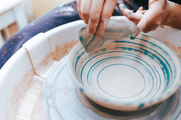 Profesyonel çömlekçi atölyedeki tabakları boyamaya çalışır. Kadın seramik tabağı fırça ve mavi boyayla boyuyor. - Fotoğraf, Görsel
