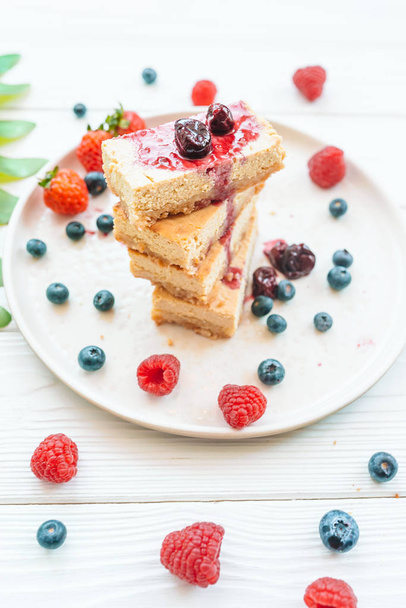 Slice of classic cheesecake with fresh berries on the white plate - healthy organic summer dessert. - Foto, Imagen