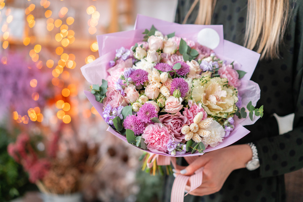 European floral shop. Beautiful bouquet of mixed flowers in womans hands. the work of the florist at a flower shop. Delivery fresh cut flower. - Foto, Imagen