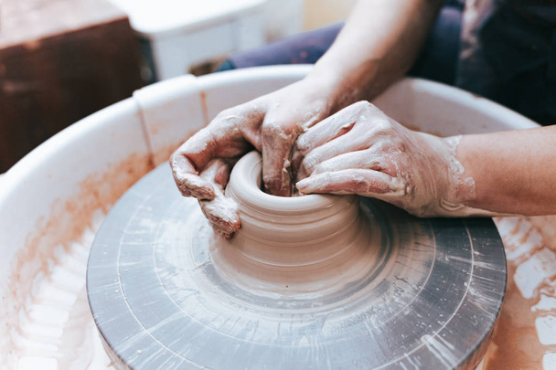 Processo de criação e formação de uma placa de cerâmica de barro branco. O oleiro profissional está envolvido na modelagem de placas de argila. Potter trabalha em uma oficina
 - Foto, Imagem