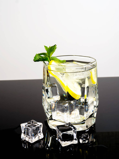 Vodka with lemon and ice on a black background - Photo, image