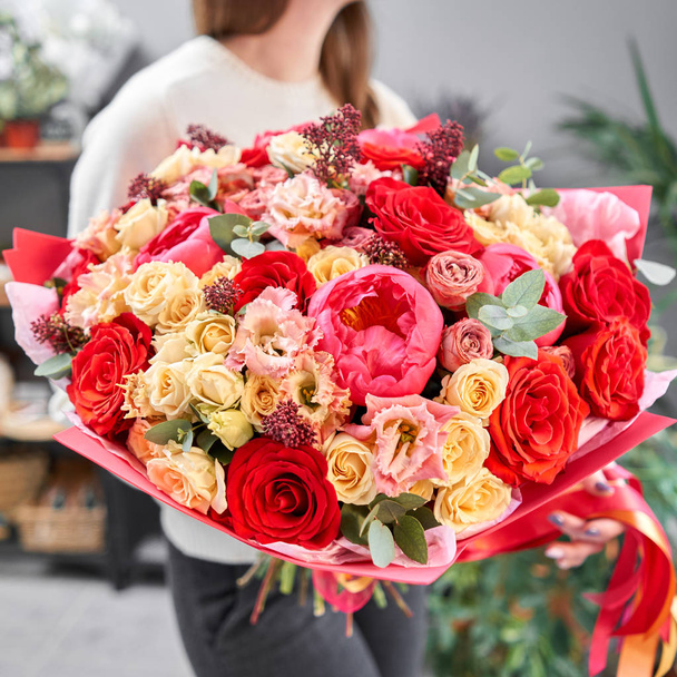 赤いトーン女性の手に混合花の美しい花束。花屋さんのお花屋さんの仕事。新鮮な花束を。花配達 - 写真・画像