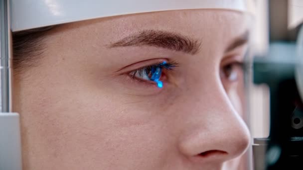 Augenheilbehandlung - eine junge Frau überprüft ihre Sehschärfe mit einem anderen farbigen Licht einer speziellen großen Optometrie-Maschine - braune Augenfarbe - Filmmaterial, Video