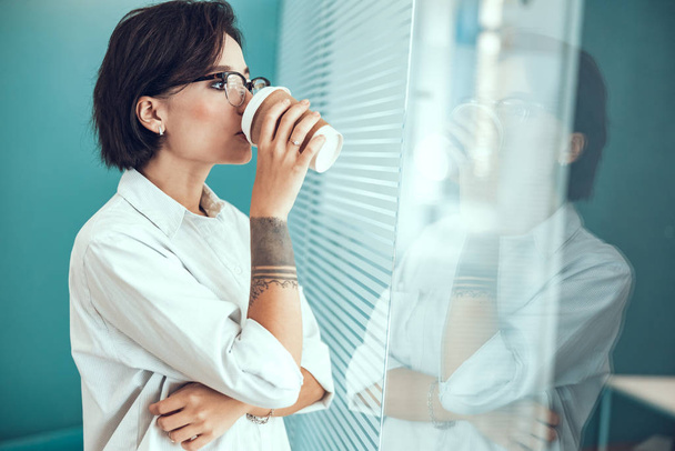 Female worker is drinking coffee in office - Fotografie, Obrázek