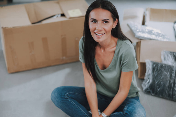 Счастливая молодая женщина сидит рядом с картонными коробками
 - Фото, изображение