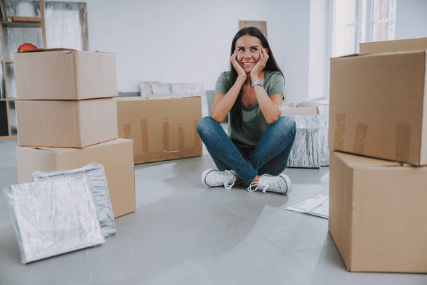 Smiling woman sitting in the middle of cardboard boxes - Foto, Imagem