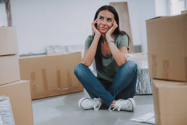 Smiling pretty woman sitting near boxes in room - Foto, Imagem