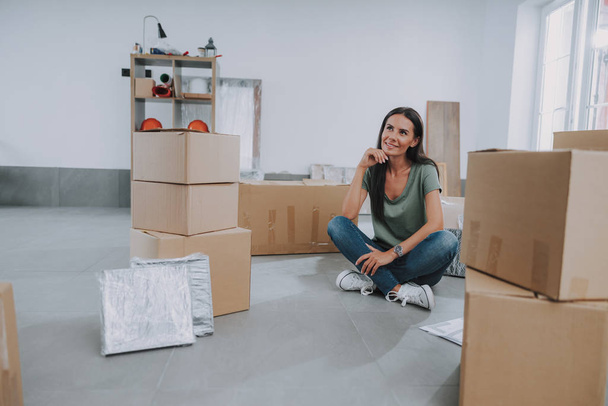 Young woman packing boxes while moving house - Zdjęcie, obraz