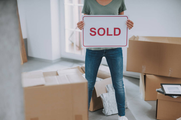 Woman is holding sold sign in her hands at home - Foto, Imagen