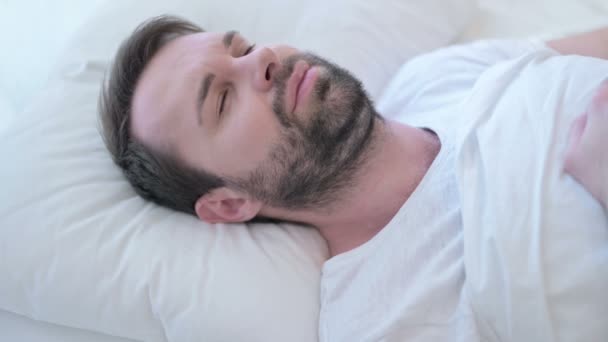 ベッドで首の痛みを持つ寝ひげの若い男  - 映像、動画