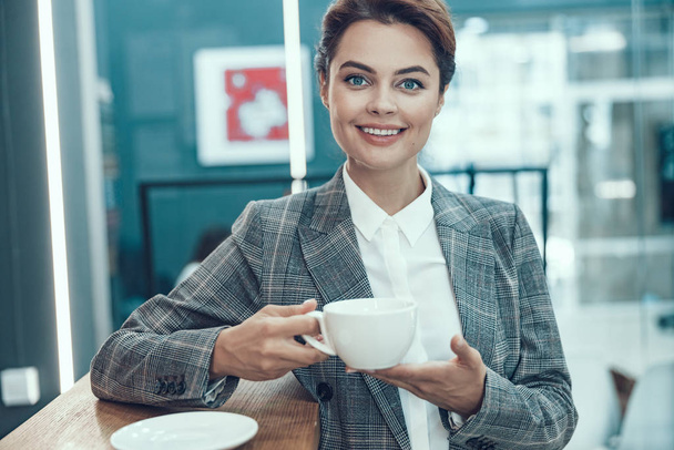 Enjoying hot drink at work and smiling stock photo - Фото, изображение