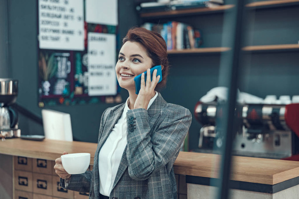 Woman with cellphone in small coffee point stock photo - Zdjęcie, obraz