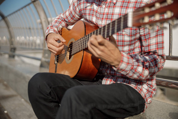 Musician playing guitar and sitting in the city - Φωτογραφία, εικόνα