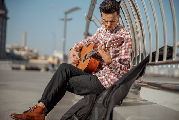 Stylish street musician is playing guitar outdoors - Zdjęcie, obraz