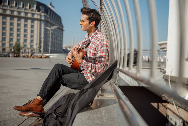 Male musician playing guitar on the square - Fotoğraf, Görsel