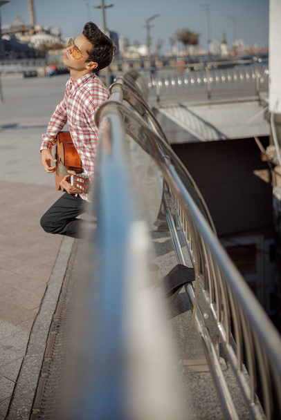 Musician playing guitar and standing in the city - 写真・画像
