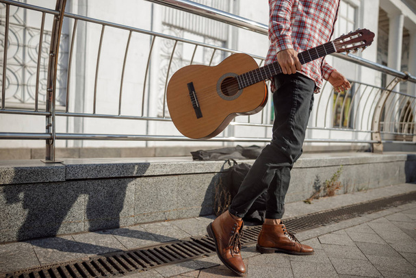 Young guitarist walking in the street with his instrument - Fotoğraf, Görsel