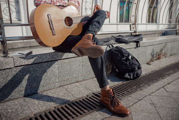 Young guitarist sitting and resting with guitar outdoors - Fotó, kép