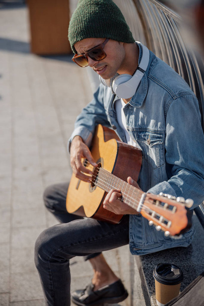Smiling guitarist in hat playing song on the street - Fotoğraf, Görsel