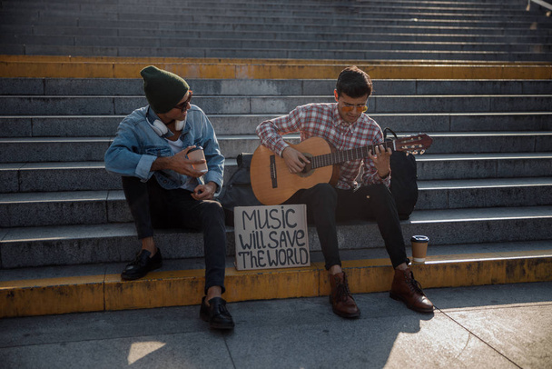 Smiling guys enjoying music on the street - Фото, изображение