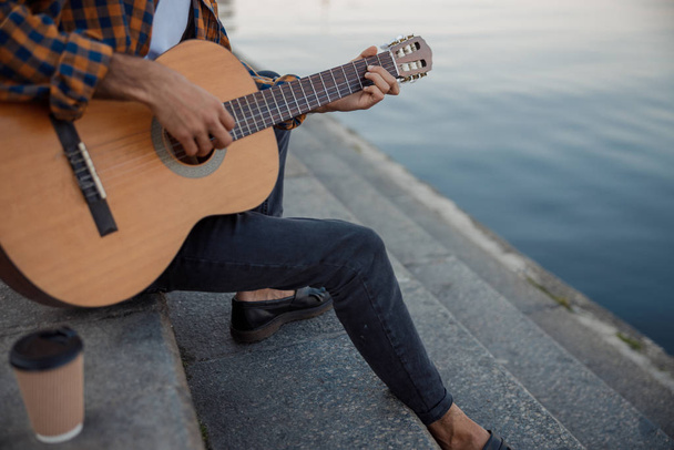 Male guitarist is sitting on steps outdoors - Photo, Image