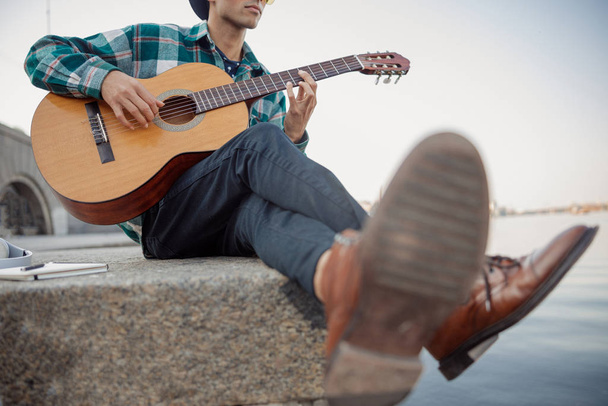 Guitarist holding guitar while looking away outdoors - Foto, Bild