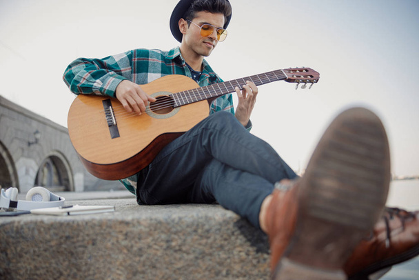 Musician playing the guitar near the river - Φωτογραφία, εικόνα