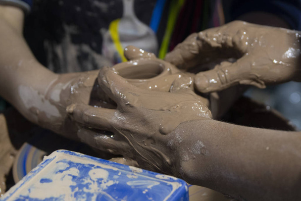 Жінка і дитячі руки роблять глиняний горщик
 - Фото, зображення