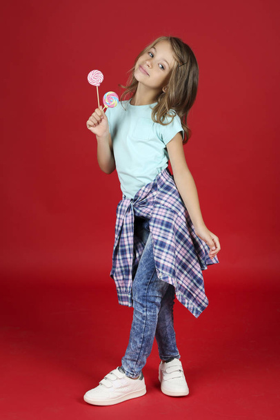 Young girl in fashion clothing with lollipops on red background - Foto, immagini