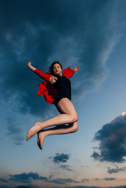 Νεαρή γυναίκα χορεύτρια μπαλέτου, ενώ πηδάει ψηλά στον αέρα - Φωτογραφία, εικόνα