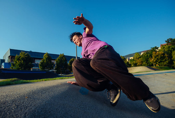 Sportlicher Mann mit Parkour-Akrobatik im Skatepark - Foto, Bild