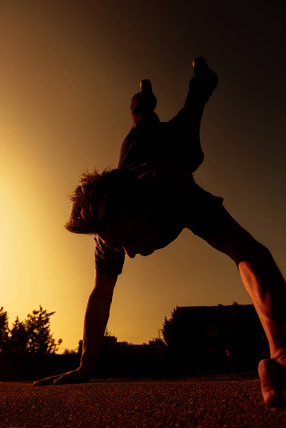 athletischer Silhouette-Typ bei einer Handstandübung im städtischen Skatepark - Foto, Bild