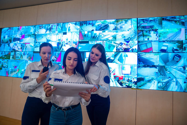 Ana kontrol odasındaki büyük bir CCTV monitörünün önünde duran güvenlik görevlileri planları okuyup tartışıyorlar. - Fotoğraf, Görsel