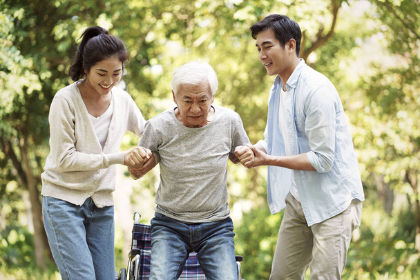 young asian couple helping old man stand up - Photo, Image