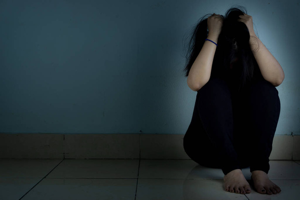 mujer triste abrazar su rodilla y llorar sentado solo en una habitación oscura. Dep.
 - Foto, Imagen
