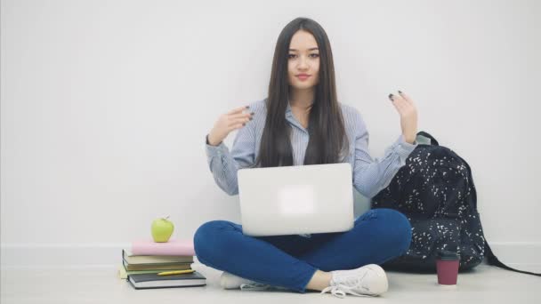 Joven asiática sentada en el suelo en posición lotos, con laptop, levantando las manos con copyspace para texto o producto, ponderación
. - Imágenes, Vídeo