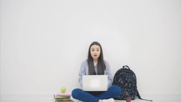Uroczy uśmiechnięty azjatycki student siedzi na podłodze w pozycji lotosu, z laptopem, wskazując palcami w górę, uśmiechnięty. - Materiał filmowy, wideo
