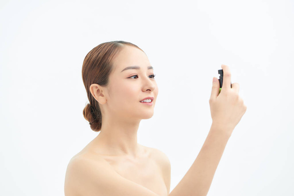 Beautiful asian woman applying spray water on face isolated white background. - Φωτογραφία, εικόνα