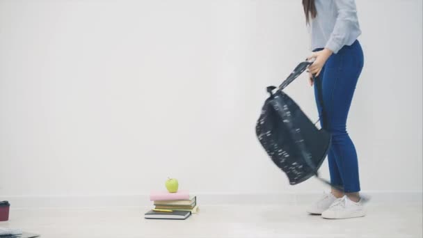 Adorable young asian girl appearing on white background, sitting down on the floor in lotos position, waving hello, openig up her backpack, taking out sketchbook. - Footage, Video