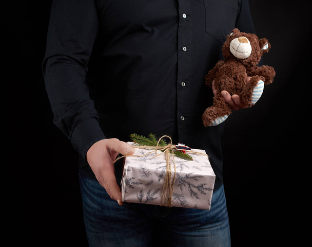 dospělý muž v černé košili drží čtvercovou krabici a hnědý Teddy být - Fotografie, Obrázek