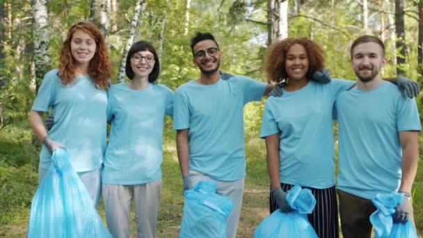 Movimento lento de jovens amigos eco voluntários no parque com sacos de lixo sorrindo
 - Filmagem, Vídeo