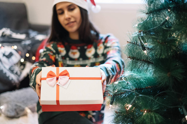 Blurred woman holding on focus Christmas present - Фото, зображення