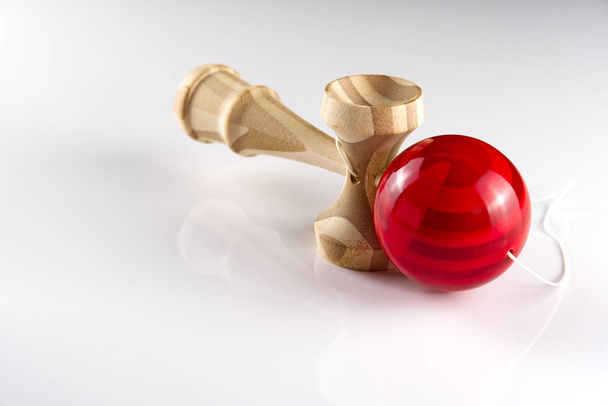 Kendama juguete japonés de madera en aislado en blanco. Juguete de madera con bal rojo
. - Foto, Imagen