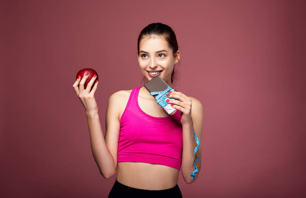 Smiling sportswoman eats chocolate with pleasure. - Photo, image