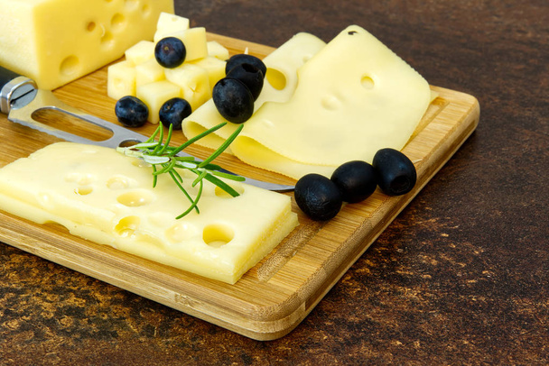 Tahtada dilimlenmiş zeytinli ve biberiyeli peynir. şarap peyniri aperatifi - Fotoğraf, Görsel