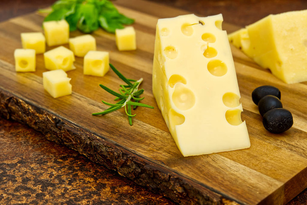 Tahtada dilimlenmiş zeytinli ve biberiyeli peynir. şarap peyniri aperatifi - Fotoğraf, Görsel
