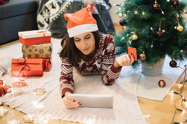 Girl with Santa hat lying on floor with tablet - Photo, Image