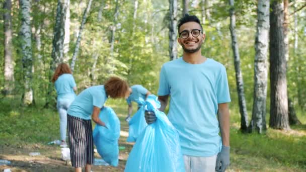 Portret van Afro-Amerikaanse man in vrijwilligersuniform met vuilniszak in park - Video