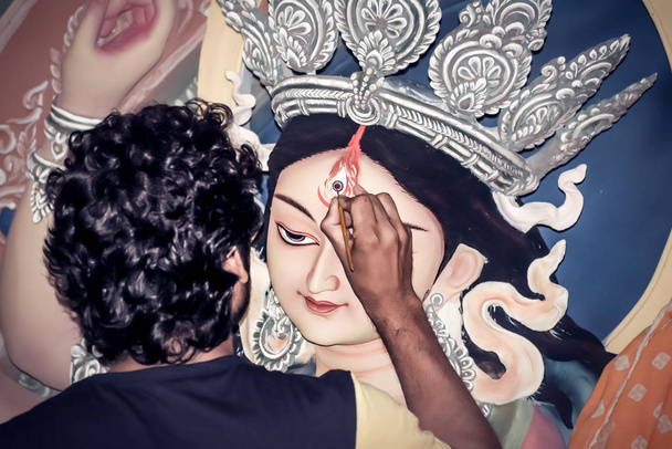 Pintura del ojo sobre arcilla ídolo de la diosa hindú Durga. Un proceso de fabricación de ídolos del artista de la cerámica en Kumartuli durante el Festival Durga Puja. Calcuta. Bengala Occidental, India
 - Foto, imagen